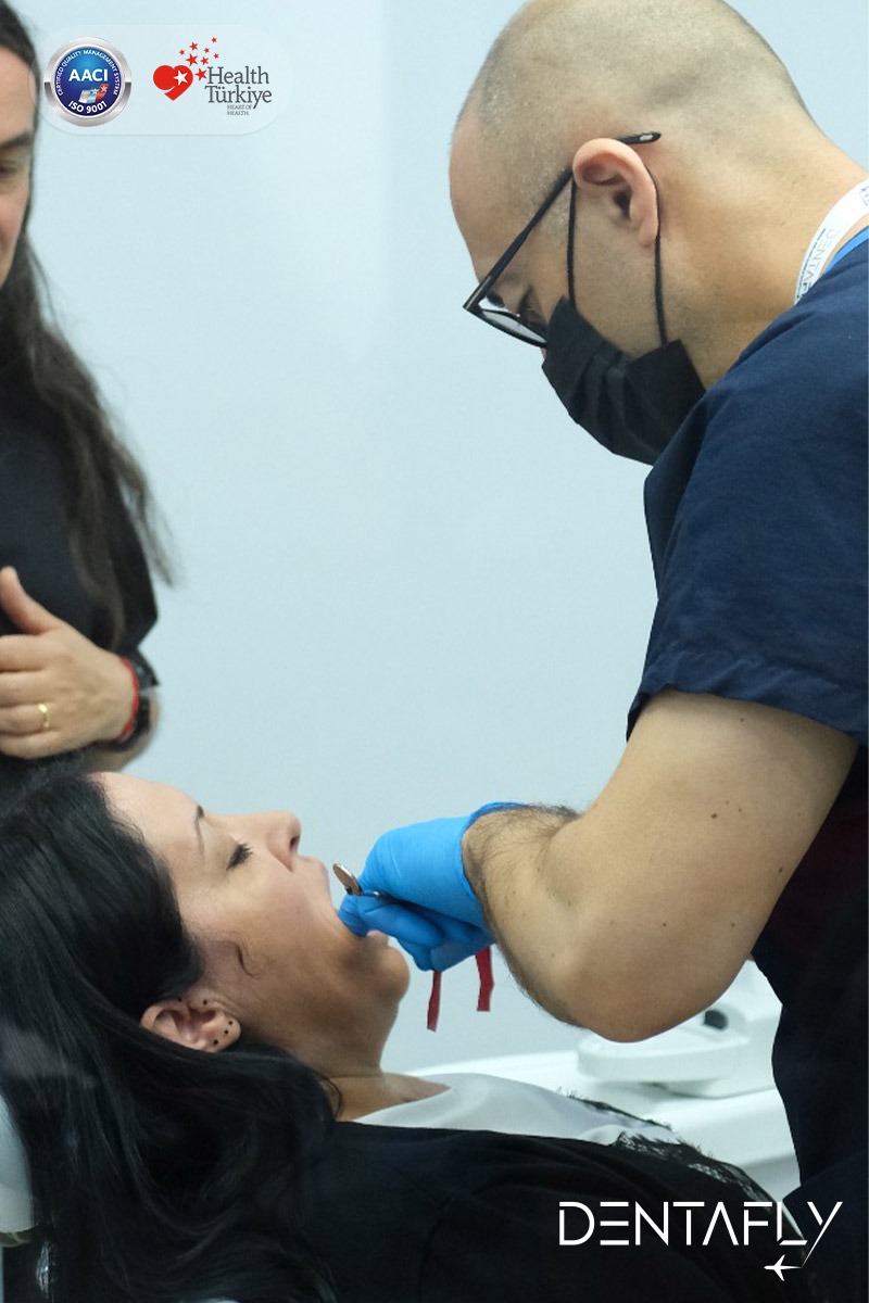 Dr. Burak Gökdeniz performing hands-on dental procedure on female patient