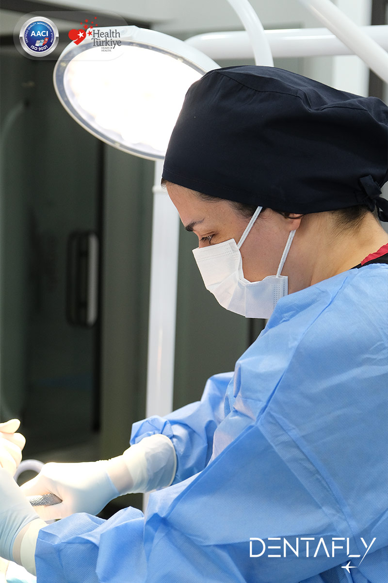 Asst. Prof. Dt. Gülen Kamak performing periodontal surgery in sterile gown at Dentafly Antalya Turkey periodontist clinic