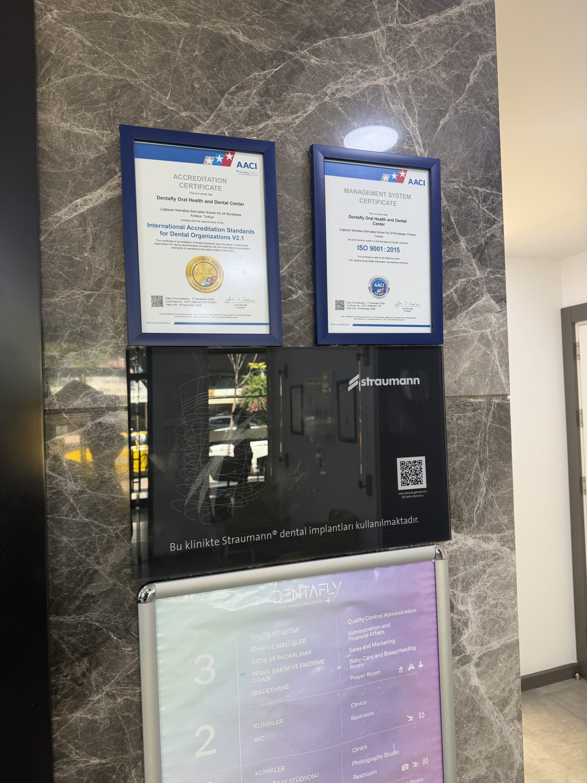 Official Straumann clinic plaque at Dentafly Antalya displayed with AACI accreditation and ISO 9001:2015 certificates